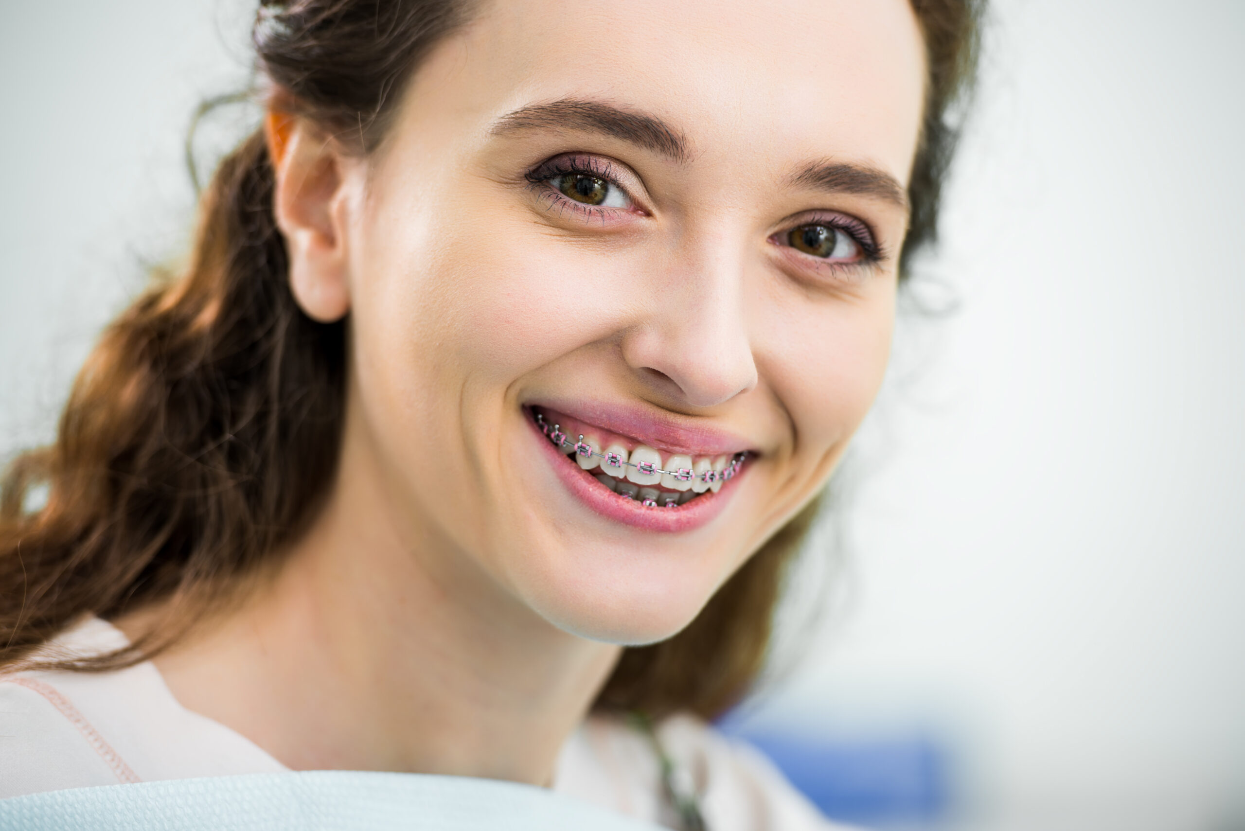 a girl smiling after attached her braces aligners in League City